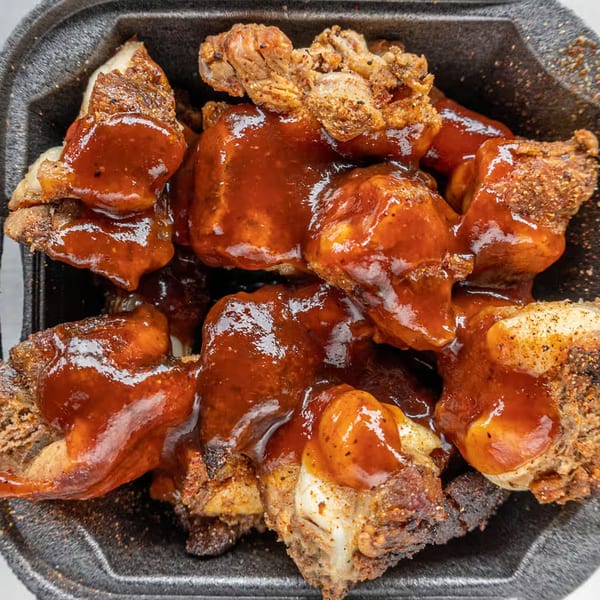 Close-up of Alabama Que's BBQ rib tips, generously coated in a rich, glossy sauce.