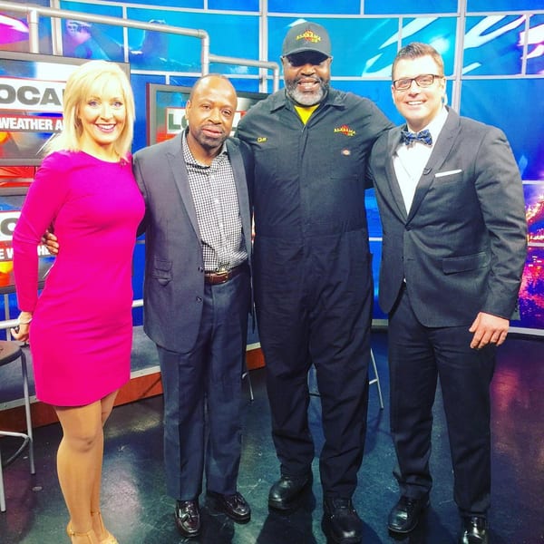 Four people, including the Alabama Que owner in a black jumpsuit, pose in a TV studio.